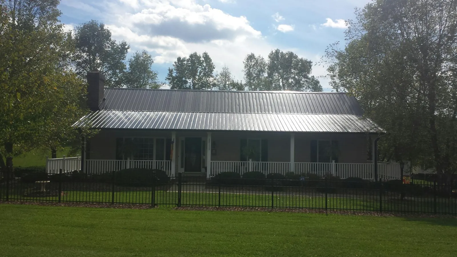Gray metal roof on a brick ranch with a full width front porch — Gutter Guard Installation work by our crew in Hendersonville