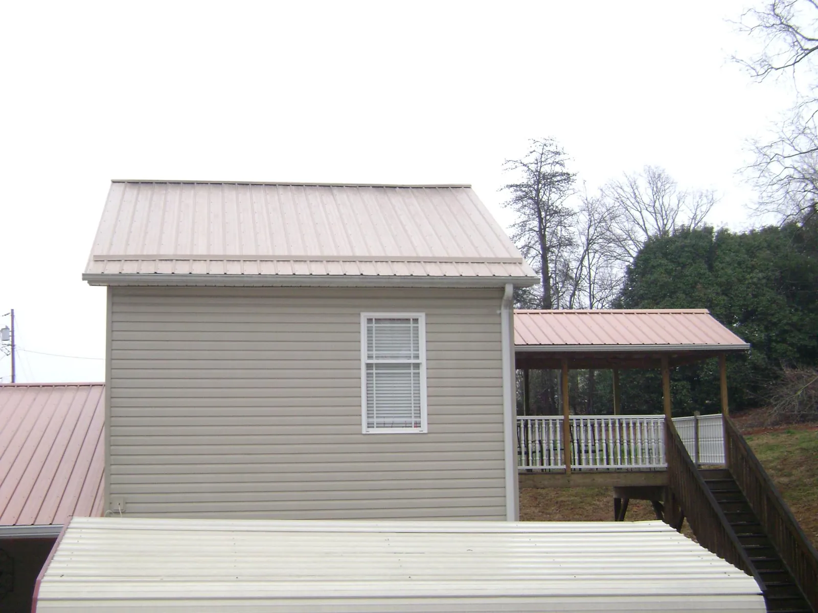 Tan metal roofs on a two story addition and attached porch, from a Roof Replacement job in Hendersonville