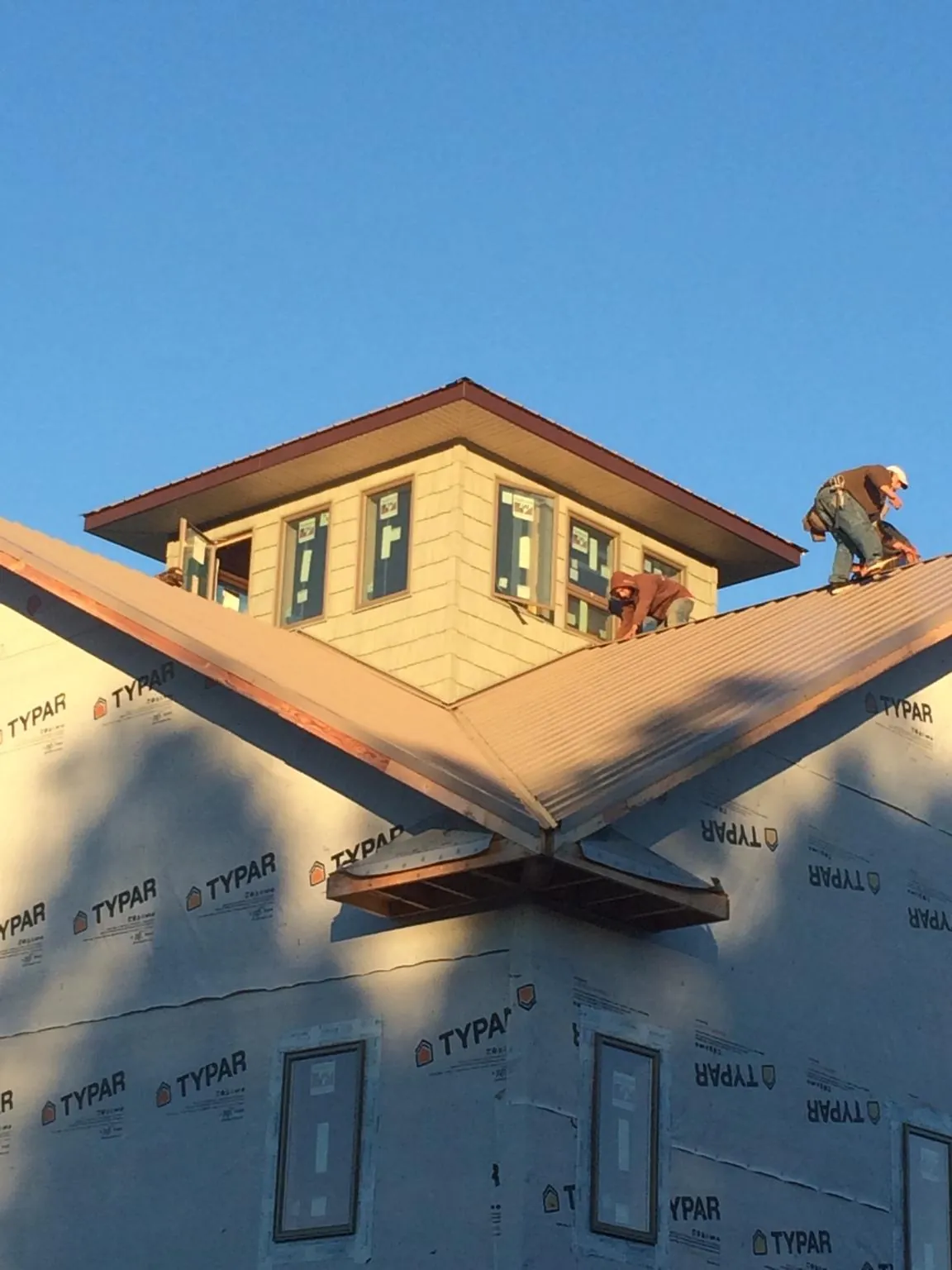 Roofers working around a rooftop cupola on a new metal roof at sunset — Roof Waterproofing in Hendersonville by Roofing Brothers